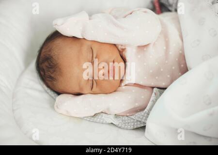 Upper view photo of a newborn baby sleeping in bed wearing cute clothes Stock Photo