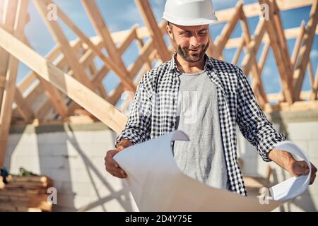 Gladsome engineer looking at a building plan on paper Stock Photo