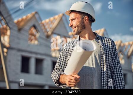 Cheerful architect looking proud while carrying a building plan Stock Photo
