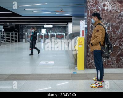 Moscow. Russia. October 5, 2020. A teenage guy in a face mask stands in the lobby of a subway station. A special automatic hand sanitizer is installed Stock Photo
