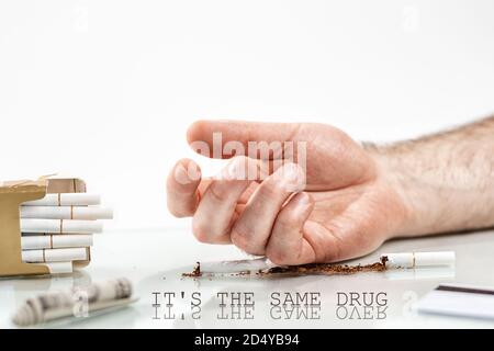 The concept of nicotine dependence. On the surface lies a broken cigarette, a dollar bill and a pack of cigarettes, near which lies a man's hand. Whit Stock Photo