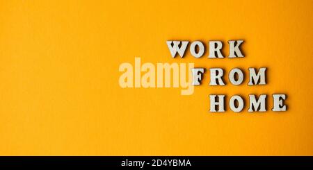Wooden letters text WORK FROM HOME in front yellow background, copy space, banner for freelance coronavirus quarantine isolation Stock Photo