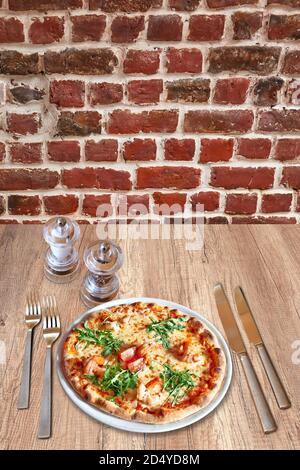 Rustic wooden table with a set of silverware , White plate with round pizza and shrimp. Stock Photo