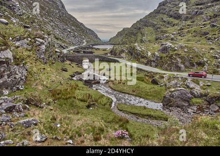 Small road winding through the gap of dunloe, Ireland. Panoramic view of the Gap of Dunloe, Ireland. Small stream flows through the Gap of Dunloe in I Stock Photo