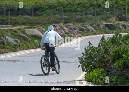 Rear view of a teenage boy wearing a hoodie riding  on a bicycling. Stock Photo
