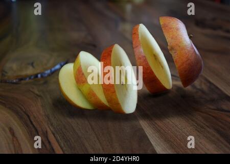 Apple slices levitating above a wooden vintage table. Levitation apple. Stock Photo