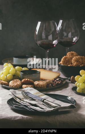 Home dinner table set with wine, cheese plate, appetizers and empty plate with cloth napkin. Stock Photo