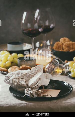 Home dinner table set with wine, cheese plate, appetizers and empty plate with cloth napkin. Stock Photo