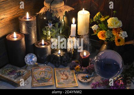 Mysterious still life with old tarot cards, crystal ball and black candles on witch table. Esoteric, gothic and occult background with magic objects. Stock Photo