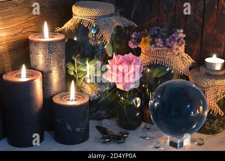 Mysterious still life with blak candles, crystal ball and rose on witch table. Esoteric, gothic and occult background with magic objects. Halloween fo Stock Photo