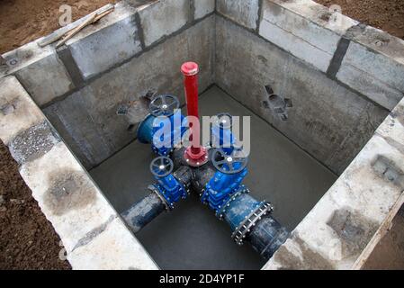Gate valves in valve pit of the underground piping networks. Laying water system pipeline at construction site. Water supply pipeline, pipes in trench Stock Photo