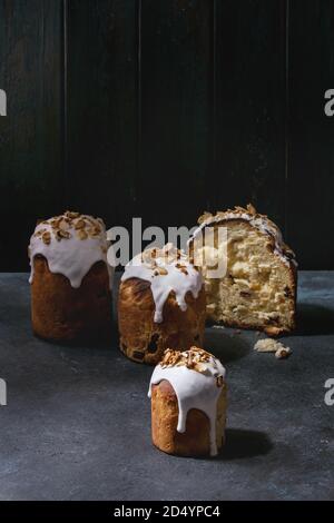 Set of traditional Russian and Ukrainian Easter cake Kulich Paska bread glazed with almond, whole and sliced over dark table. Copy space Stock Photo