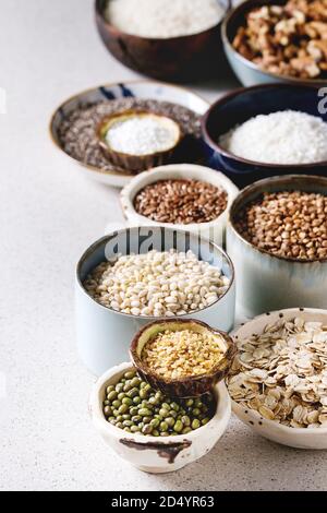 Variety of raw uncooked grains superfood cereal chia seeds, linen, sesame, mung bean, walnuts, tapioca, wheat, buckwheat, oatmeal, coconut, rice in ce Stock Photo