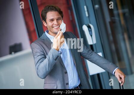 Adult businessman leaving hotel in mask due to covid-19 restrictions Stock Photo