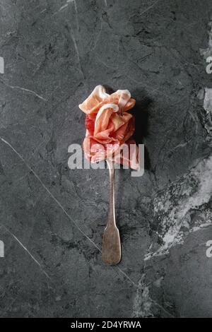 Antipasto meat assorti of sliced jamon, salami, chorizo sausage on fork over black marble background. Flat lay, space. Appetizer concept Stock Photo