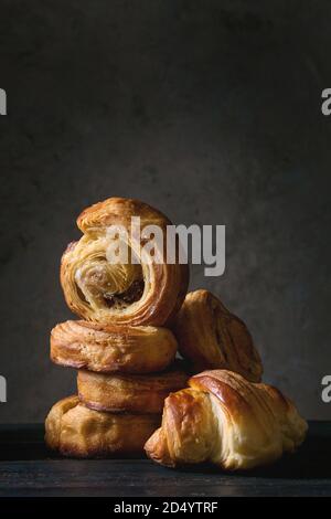 Variety of homemade puff pastry buns cinnamon rolls and croissant on wooden table. Dark still life. Copy space Stock Photo