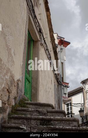 Stone steps leading to old fashioned green wooden door in small town in Galicia, Spain. Door town entrance architecture spanish stone steps. Stock Photo