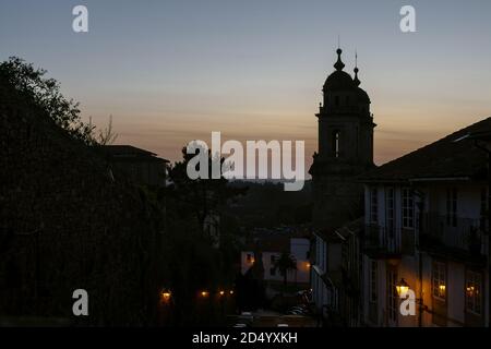 Santiago de Compostela, Galicia, Spain - 09/27/2020: Convento de San Francisco at sunset with a dimly sit street & town houses in front. Spain sunset