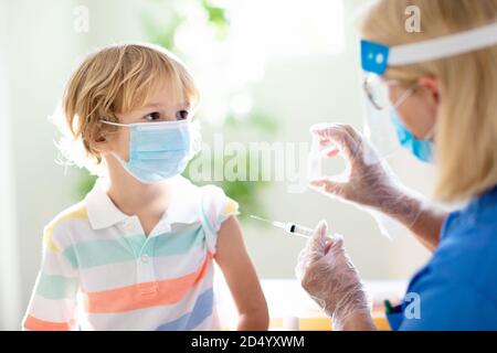 Coronavirus vaccination. Covid-19 vaccine. Doctor vaccinating child. Kids at clinic. Little boy getting flu shot. Pediatrician examining kid and givin Stock Photo