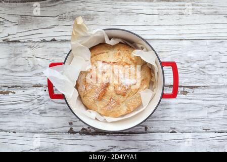 Top view of homemade artisan bread freshly baked in a red Dutch oven. Flatlay. Stock Photo