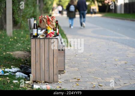 Overcrowded trash basket in the street. Garbage bin. A pile of plastic waste trash on the floor and grass. Stock Photo