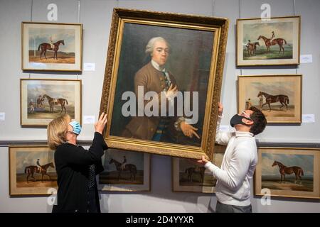 Deborah Hood (left) and Jamie Russell hang an 18th Century French oil painting depicting a young man in brown frock coat and waistcoat (estimate £1,500-£2,000) alongside other 18th and 19th Century works which are all contents from Beal House, a Grade II listed manor house in the Vale of York, which will be sold at auction by Lyon and Turnbull, Edinburgh, in a two day sale on the 14 and 15 October, 2020. Stock Photo