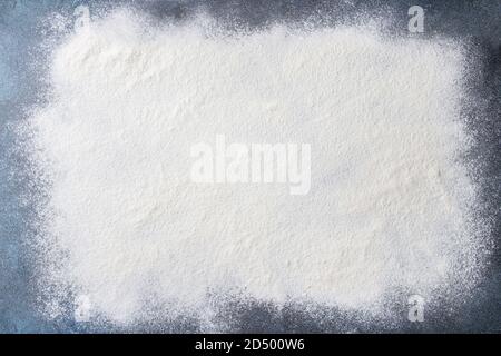 Sifted wheat flour over dark blue texture surface. Food background. Stock Photo
