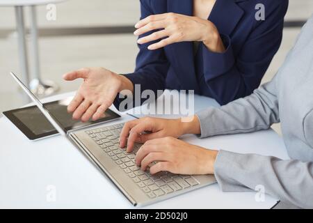 Cropped portrait of two successful businesswomen discussing work and gesturing and using laptop together, copy space Stock Photo