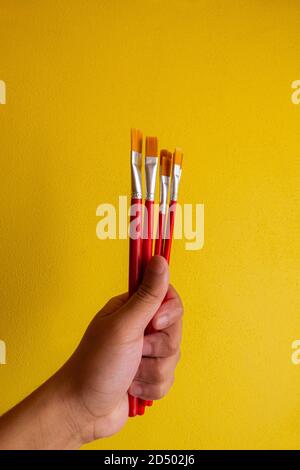 man hand holding six paintbrushes together