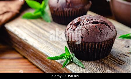 Chocolate cupcake muffin with mint leaves in rustic style. Fresh baked chocolate muffins with no top on dark wooden background.Mint Cupcakes with copy Stock Photo