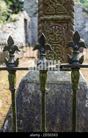 Fleur de lys shaped tips on wrought iron railings and celtic design on the base of a cross behind, County Kildare, Ireland Stock Photo