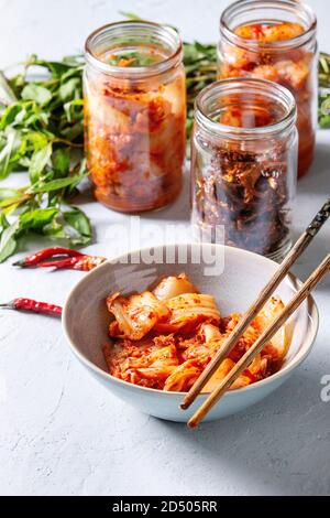 Korean traditional fermented appetizer kimchi cabbage and radish salad, hot spicy anchovies fish snack served in glass jars and bowl with Vietnamese o Stock Photo