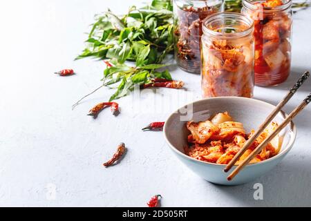 Korean traditional fermented appetizer kimchi cabbage and radish salad, hot spicy anchovies fish snack served in glass jars and bowl with Vietnamese o Stock Photo