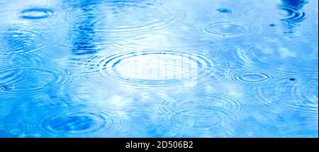 Stains circles on water from rain. Raindrops on pool blue water surface. blue water texture as background. Long web baner Stock Photo