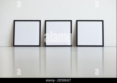 Background image of three identical black frames set against white wall in row at art gallery, copy space Stock Photo
