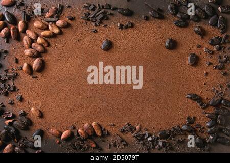 Variety of fresh and dry cocoa beans with chopped dark chocolate over cocoa powder as background. Chocolate concept Stock Photo