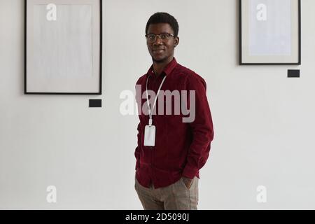 Portrait of young African-American man looking at camera with hands in pockets while working at art gallery or exhibition, copy space Stock Photo