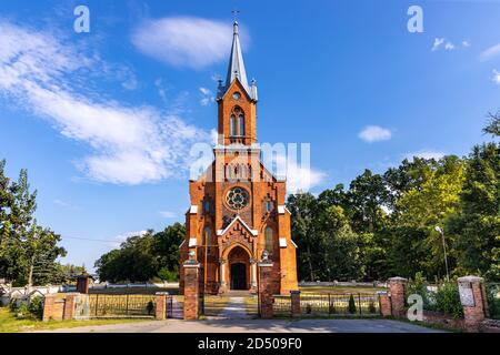 Naglowice, Swietokrzyskie / Poland - 2020/08/16: Neo-gothic parish church of St. Mary Rosary near park and historic museum manor house of Mikolaj Rej, Stock Photo