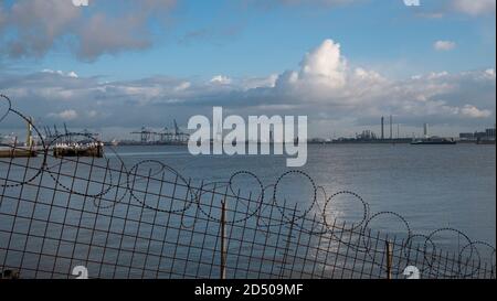 Doel, Belgium, October 10, 2020, The Port of Antwerp early in the morning on a foggy day with barbed wire in the foreground Stock Photo