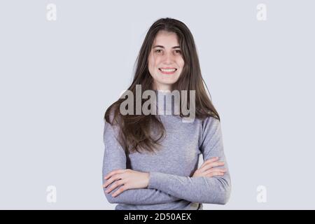 Smiling confident  young  student woman looking to camera holding hands crossed isolated over white background with copy space. Successful Student gir Stock Photo