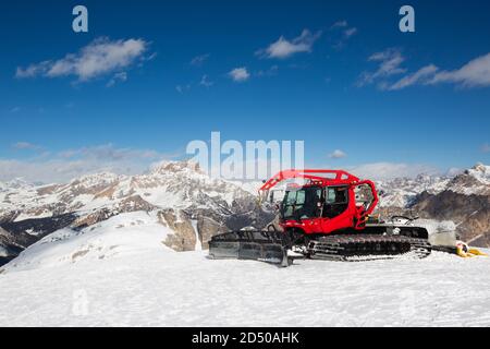 Red modern snowcat ratrack with snowplow snow grooming machine preparing ski slope piste hill at alpine skiing winter resort Cortina d'Ampezzo in Ital Stock Photo