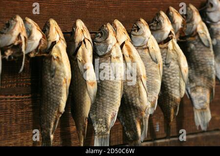 A bunch of dried salted fish hangs on a background of wooden planks Stock Photo