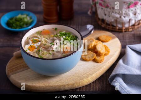 Soup with chicken, noodles, potatoes, quail eggs and carrots. Seasoned with onions and parsley. Close-up. Stock Photo