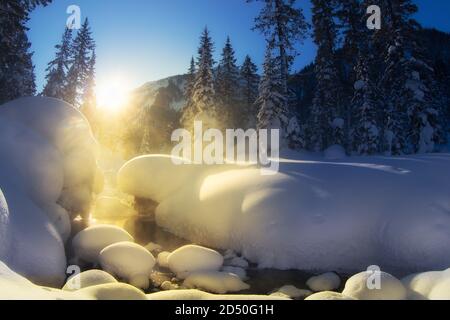 winter landscape, mountain river in winter forest, snow drifts frosty, foggy morning snow covered trees in warm glow of sunrise Stock Photo