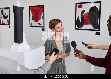 High angle portrait of elegant tattooed woman giving interview to reporters while opening modern art gallery exhibition Stock Photo