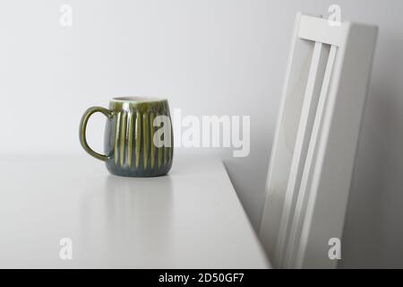 Green mug on a white table and a white chair Stock Photo