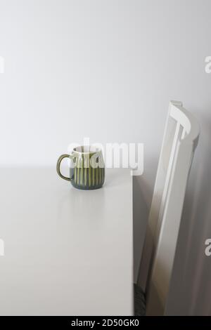 Green mug on a white table and a white chair Stock Photo