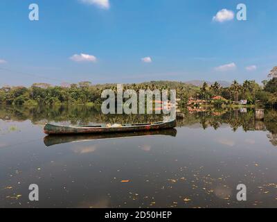 A canoe floating free in the periyar river and surrounded by lush green forest, at Thattekad in the southern Indian state of Kerala. Stock Photo