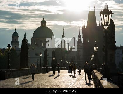 PRAGUE, CZECH REPUBLIC - SEPTEMBER 09, 2013: A few people crossing Charles Bridge (Karluv Most) early in the morning. View of the Old Town Bridge Towe Stock Photo