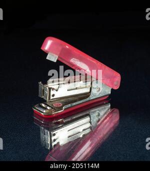 Stepler on table with reflection on black background. Instrument for joining the paper by bracket Stock Photo